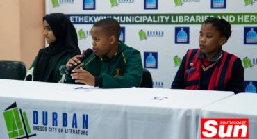 multiple children, one with a microphone in his hands answering a question