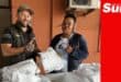 a man and a woman with a ton of donated linen from towels to sheets to pillowcases.