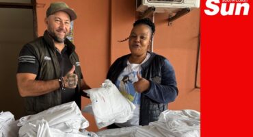 a man and a woman with a ton of donated linen from towels to sheets to pillowcases.