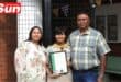 parents take a group photograph with their daughter, who shows off her award