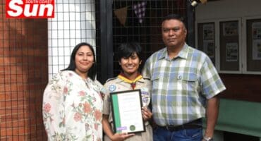 parents take a group photograph with their daughter, who shows off her award