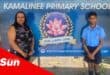 a teacher and a learner stood in front of a school signboard