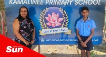 a teacher and a learner stood in front of a school signboard