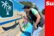 an artist painting a mural that depicts tourism activities in a coastal town
