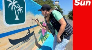 an artist painting a mural that depicts tourism activities in a coastal town