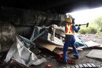 A Land Invasion worker demolishes a shack.