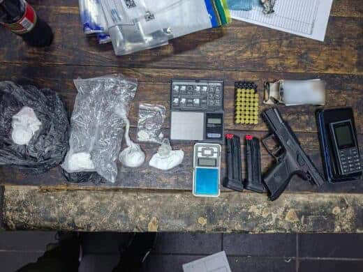 Drugs, a gun and ammunition, a cell phone and other items on a wooden table