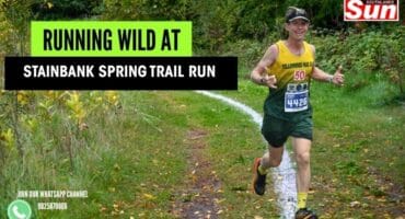 Runner celebrating as he runs through a trail.