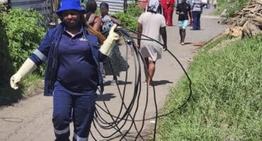Municipal employee carrying cables that were removed from the informal settlement