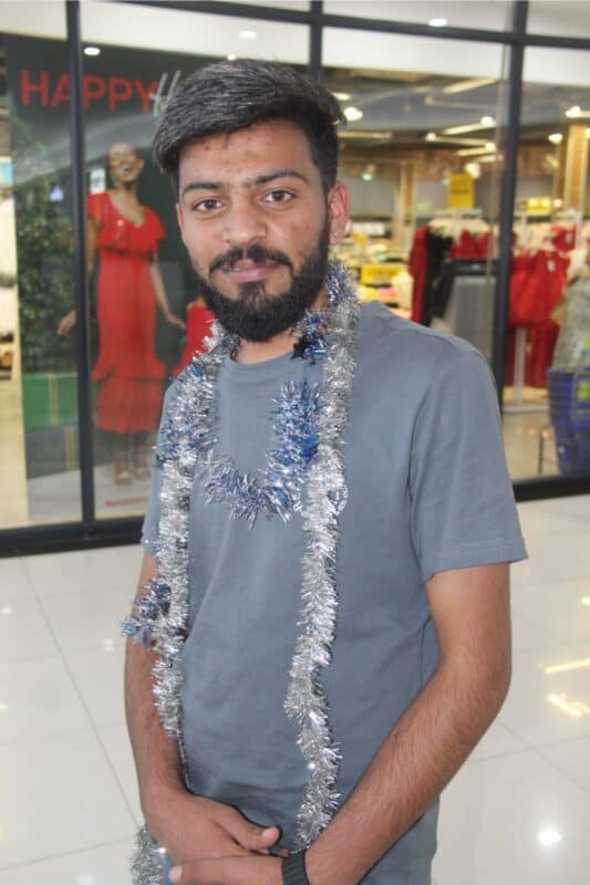 Man dressed with tinsel and a hat.