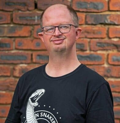 A man with glasses wearing a black t shirt with a snake print on