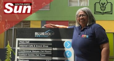 YESS co-founder and administrator Linda James stands proudly next to the Blue Roof Life Space sign.