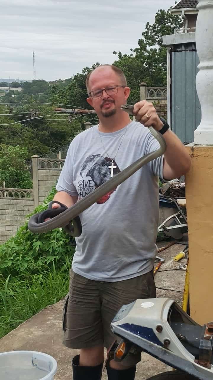 A man holding a black mamba that he captured.