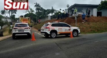 Two emergency vehicles standing in the roadway with traffic cones blocking off the road.