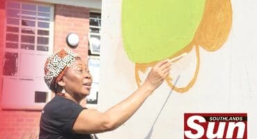 Dr. Gcina Mhlope helps paint the walls of the library.