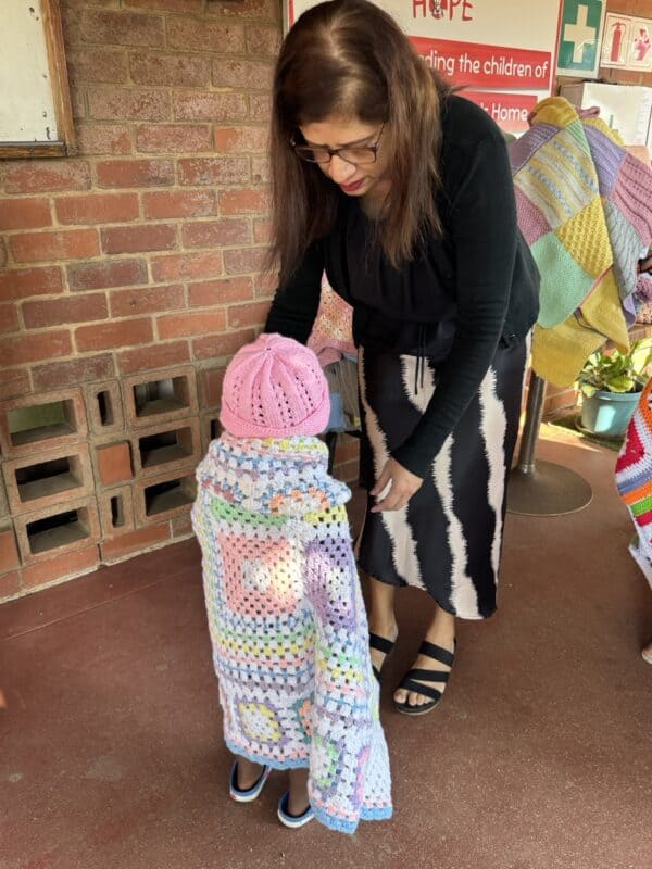 A little girl at St Monica's Children's Home gets help from St Monica's Children's Home director Althea Govender.