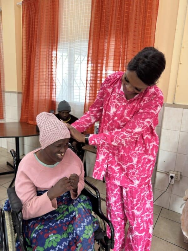 Manager of the Merewent Cheshire Home places one of the crocheted beanies on resident Ayanda Mngadi.
