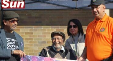 Cartoonist, Nanda Soobhen, and former principal of Clairwood Secondary School, Yugan Naidoo, present a commemorative artwork in honour of former judge and anti-apartheid activist Thumba Pillay, while his wife, Dolly Pillay, looks on.