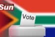 South African flag in the background with white ballot box and voting envelope