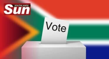South African flag in the background with white ballot box and voting envelope