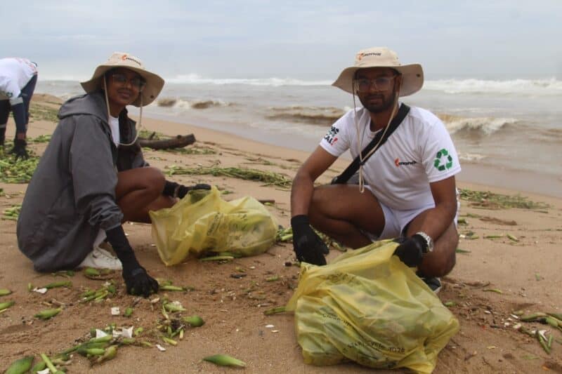 Volunteers collecting litter on the beach for environmental conservation.