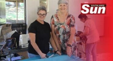 Ronel Lategan and Dawn Solomon work together to measure and cut fabric.