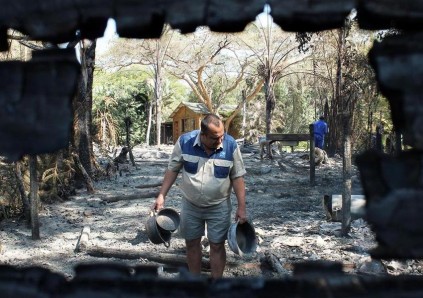 ‘n Vernietigende brand het ses houthuise by Hippo Water Front in puin gelê. Lodgebestuurder mnr. Anton Krous kyk of daar iets te redde is.