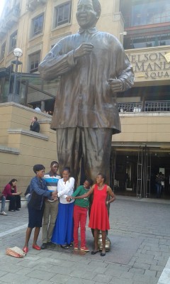 Two Conservation Fun Run winners and family at Mandela Statue in Sandton Square