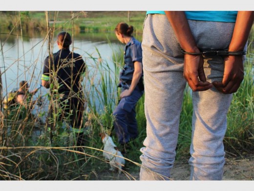 The mother who, along with the biological father, allegedly killed her 14-month-old son and dumped his body in a dam near their home. Here, she is standing with a police diver at the scene of the crime, while another diver searches for the body. Photos: Marinette Potgieter