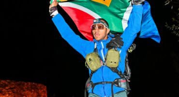 Damien Kühn carries the South African flag over the finish line. > Photo: Sourced/Ultra Gobi 400