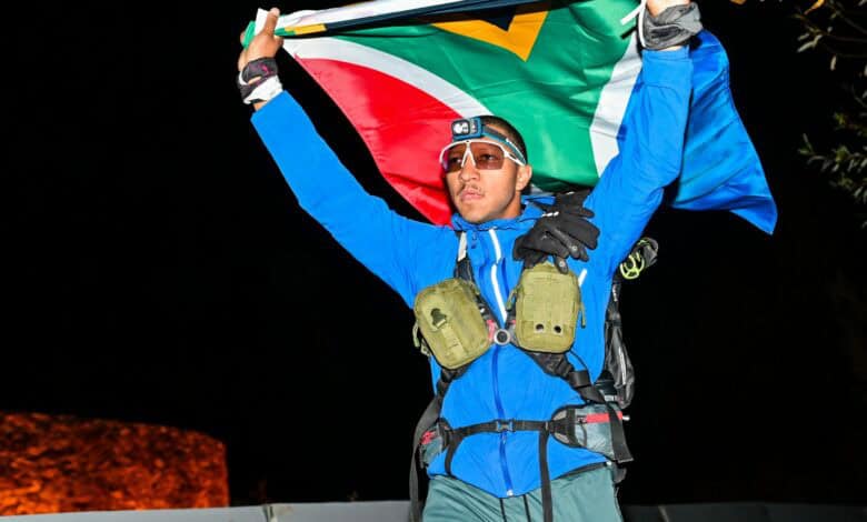 Damien Kühn carries the South African flag over the finish line. > Photo: Sourced/Ultra Gobi 400