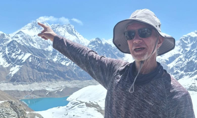 Jan Strydom on the Renjo La Pass, pointing to Everest behind him.