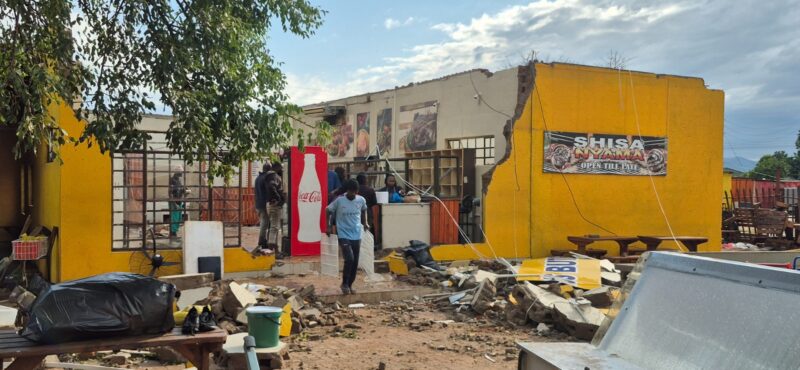 Employees remove equipment from inside the damaged building of a local business.