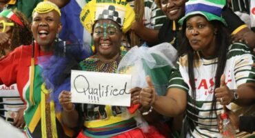 Mama Joy Chauke (middle) along with other supporters celebrate Bafana Bafana's qualification for the FIFA World Cup. > Photo: Blake Linder