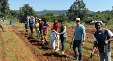 Locals and international tourists plant vegetables together.