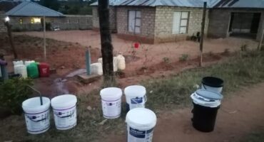 Buckets lined up for Sand River residents to collect water.