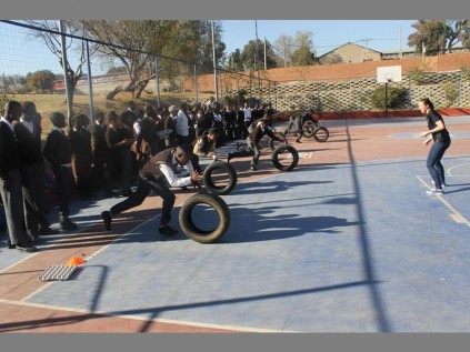Minerva Secondary School students engage in a tyre race at Three Square Sports Complex. Urging them on is Abby Thompson of Ernst & Young.