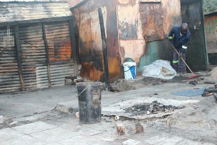 Thomas Maluleke, a resident whose shack was affected tries to clean the remains of his shack. Photo: Alulutho Siboma