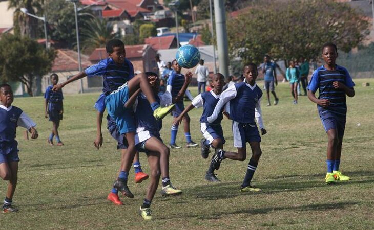 A Linda Stars player stretches high up to control the ball under a tight watch from Blue Aces defenders (in blue and white). Photo: Sipho Siso