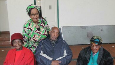Angie Makwetla, a commissioner of the SA Human Rights Commission who came to do charity work, stands behind some of the residents being catered for at the Joseph Gerard Home.
