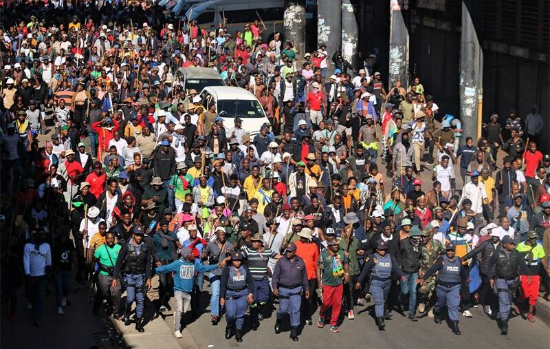 Police officers maintain walk ahead of scores of residents who decided to take it to the street to march against undocumented migrants iin Alexandra on June 30, 2026. Photo: Itumeleng Maloka