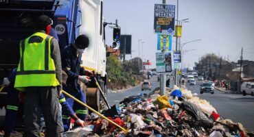 Workers of a private waste collection company clears the waste dumped on Median strip along Vincent Tshabalala Road in Alexandra on July 29, 2026.