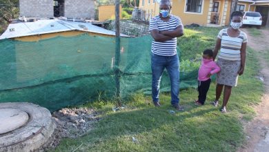 three people standing next to an overflowing sewer.