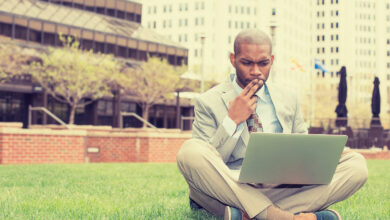 business man sitting outside corporate office working on compute