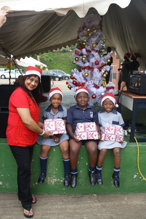 Red Hill resident Kim Naidoo who organised the event hands out presents to Columbia Primary School pupils, Ngomso Jwete, Fortune Hlnagise and Sazi Nkosi.