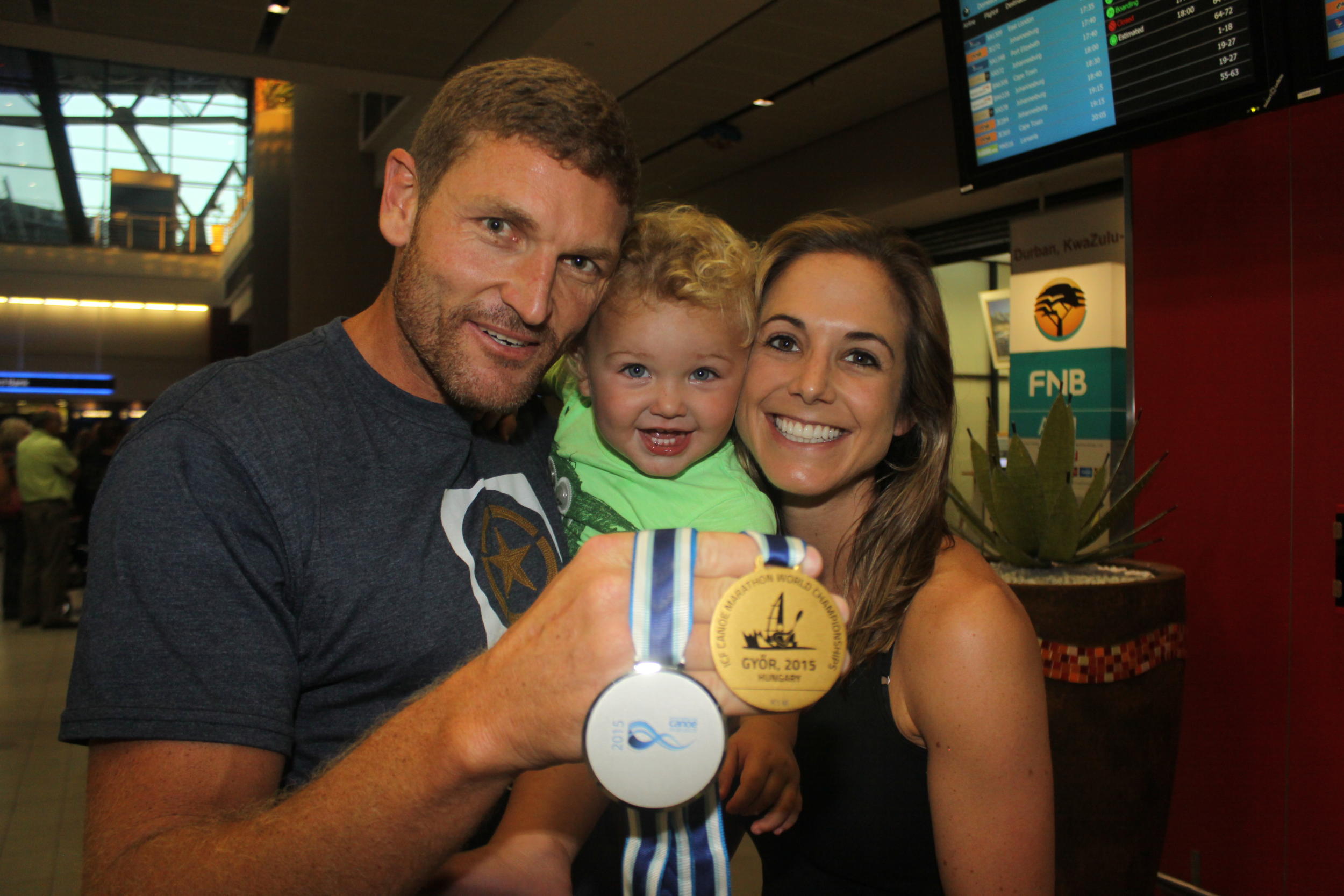 Six-time marathon canoeing world champion, Hank McGregor is welcomed home at King Shaka International Airport by his one-year-old son, Thorsten, and his wife, Pippa, after picking up men's K1 gold and K2 silver medals in the world championships in Hungary. PHOTO: Dave Macleod (Gameplan Media)