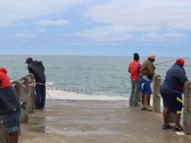 The railing at the end of the pier has been washed away. The only thing preventing fishermen from falling in is a piece of caution tape.