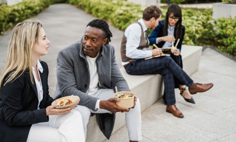 Multiethnic business people doing lunch break outdoor from office building - Focus on african man face