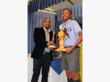 Avela Mbele of PS Senior Primary receives the sports boy of 2013, as well as ‘sports and academics all rounder’ of 2013 awards from HCM youth manager Phumlani Mzobe. PHOTO BY PRAGASEN SAMUEL.