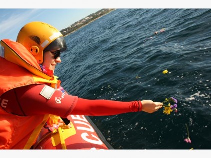 Bianca van Zyl from NSRI throws flowers into the ocean at the Paddle Out for Sharks.